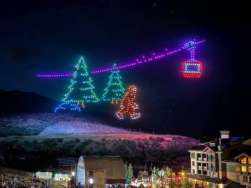 Spectacle de drones en station de ski dessinant des sapins, un skieur et une télécabine au-dessus des pistes